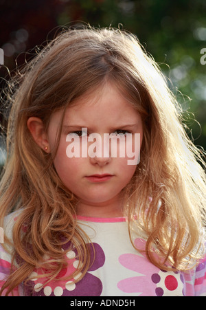 Kopf und Schultern Schuss ein sieben Jahre altes Mädchen runzelte die Stirn, in einer schlechten Stimmung oder schmollen. Stockfoto