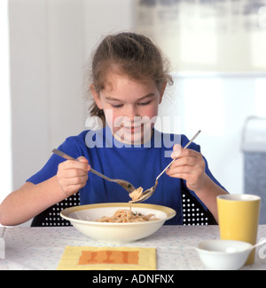 Mädchen, die Pasta mit Löffel und Gabel zu essen Stockfoto