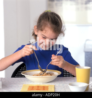 Mädchen, die Pasta mit Löffel und Gabel zu essen Stockfoto