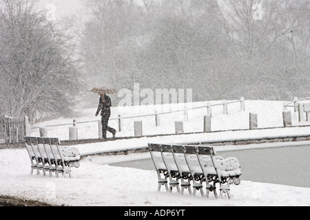 Mann bedeckt geht mit Regenschirm über Schnee Hampstead Heath North London Vereinigtes Königreich Stockfoto