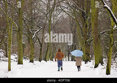 Winter-Szene bedeckt als Paar zusammen über Schnee Fuß Hampstead Heath North London Vereinigtes Königreich Stockfoto