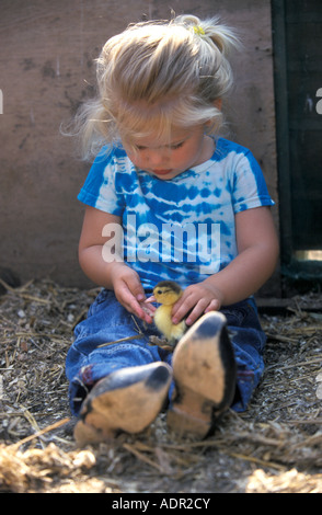 Kleines blondes Mädchen mit eine kleine Ente auf dem Schoß Stockfoto