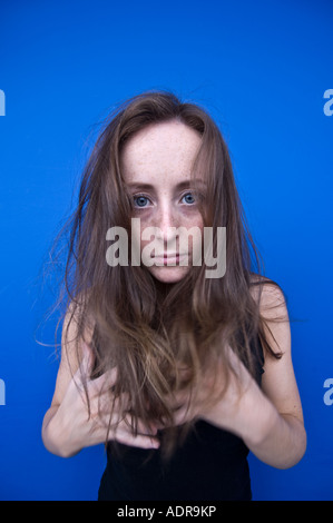 wild aussehende rote behaarte Rothaarige Sommersprossen Gesicht Frau vor blauem Hintergrund Stockfoto