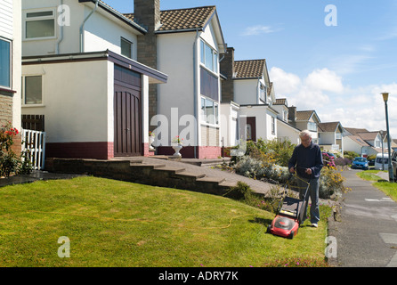 ältere alte Mann mähen Rasen vor dem Haus an warmen sonnigen wales Sommernachmittag in der Vorstadt - Aberystwyth uk Großbritannien Stockfoto