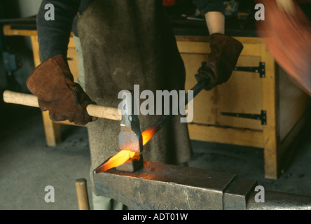 Person mit Hammer und Amboss, roten heißen Stahl in einer Schmiede s schmieden Stockfoto