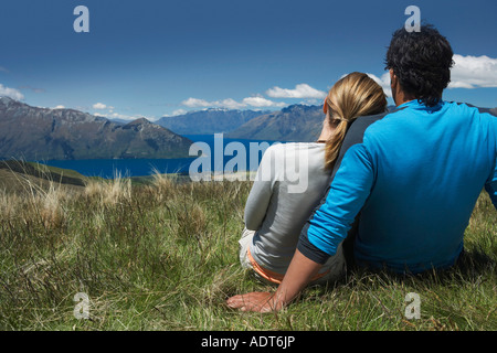 Paar kuscheln mit Blick auf See und Berge, Ansicht von hinten Stockfoto