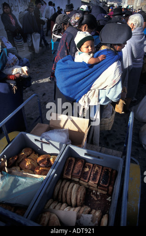 Frau in tribal Kostüm Baby auf ihrer Rückseite Brot- und Gebäcksorten Otavalo Markt Südamerika Stockfoto