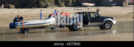 Gorran Haven Strand Nahaufnahme von Menschen & 4x4 Pickup LKW Traktor & Anhänger laden aufblasbares Boot am Ufer Auf festem Sand Cornwall England Großbritannien Stockfoto