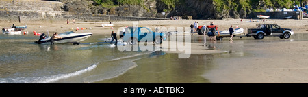 Gorran Haven Strand & Hafenmauer Menschen 4x4 Auto Abholung LKW Traktor & Anhänger laden aufblasbare Boote Geschwindigkeit Boot an Waters Edge Cornwall England Großbritannien Stockfoto