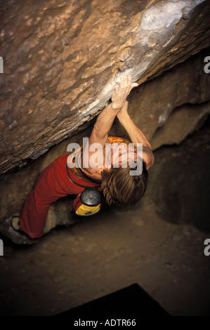 Frau Bouldern auf einem steilen überhängenden Felsblock Problem. Stockfoto