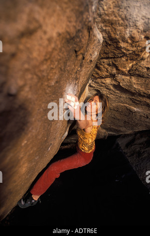 Frau Bouldern auf einem steilen überhängenden Felsblock Problem. Stockfoto