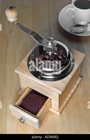 Kaffeemühle mit Bohnen und Gelände Tasse Kaffee Stockfoto
