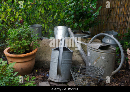 Alten Gießkannen und Blumentopf stehen in einem Garten Stockfoto