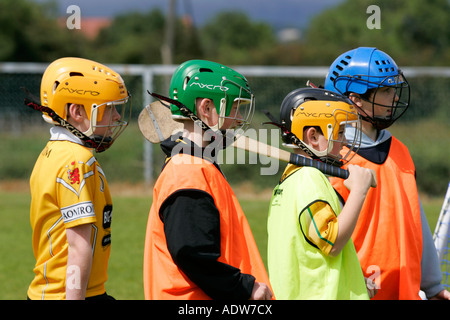 jungen tragen Schutzhelme, die man mit einem Stick Anleitung Gälische Spiele hören Stockfoto