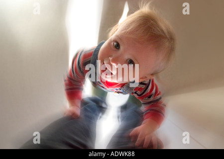 Stehen durch das Festhalten an den Beinen Mutter lernt ein lächelnder ein Jahr alt Stockfoto