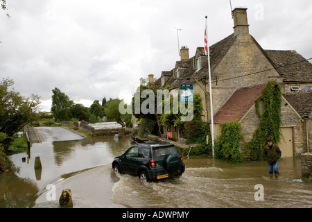 Mit dem Geländewagen fahren Auto fährt durch überflutete Straße in Swinbrook Oxfordshire in England Vereinigtes Königreich Stockfoto