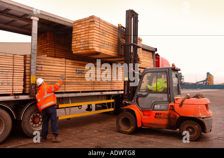 EINE GABELSTAPLER HEBT HOLZ AUF EINES SATTELSCHLEPPERS AUF DAS DOCKSIDE EINEN HAFEN IN NEWPORT SOUTH WALES UK Stockfoto