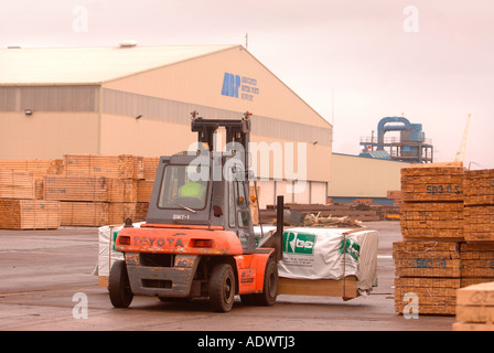 EINE GABELSTAPLER HEBT HOLZ AUF DAS DOCKSIDE EINEN HAFEN IN NEWPORT SOUTH WALES UK Stockfoto