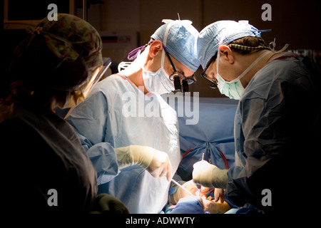 2 zwei Gefäßchirurgen Ausführung einer Operation am Arm des Patienten und unterstützt von einer Krankenschwester in den Schatten Stockfoto