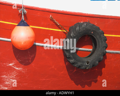 Bouy und alten Reifen hängen neben den Rumpf eines rot Fischerbootes Stockfoto