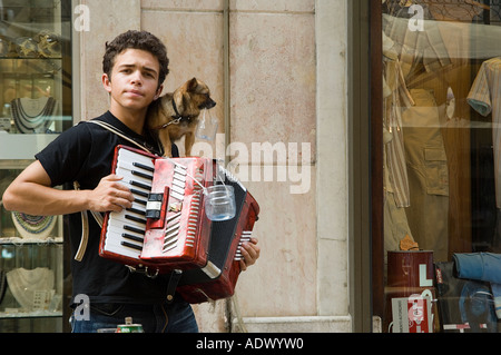 Straßenmusik junger Mann spielt Akkordeon, mit kleiner Hund auf seiner Schulter, die Tipps zu sammeln. Lissabon, Portugal. Stockfoto