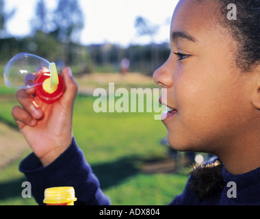 Kinder kleine schwarze junge Mädchen spielen Bubbles Seife Seifenblase weht Spielzeug Spaß hält Blase Ausdruck Emotion Menschen p Stockfoto