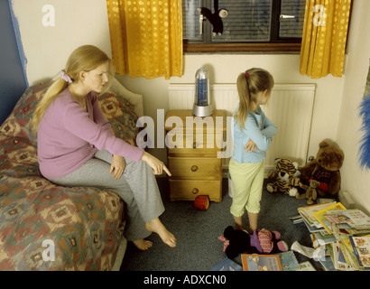 Mutter erzählte Sie ihr Kind in ihrem chaotisch Schlafzimmer Stockfoto