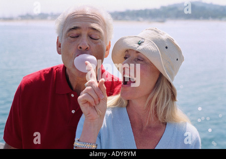 Mann bläst Bubble Gum, Frau versucht, Bubble Burst Stockfoto