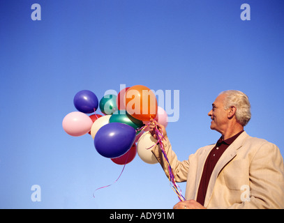 Mann hält Haufen Luftballons Stockfoto