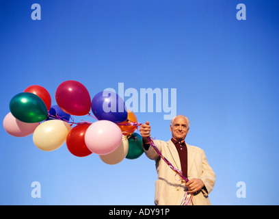 Mann hält Haufen Luftballons Stockfoto