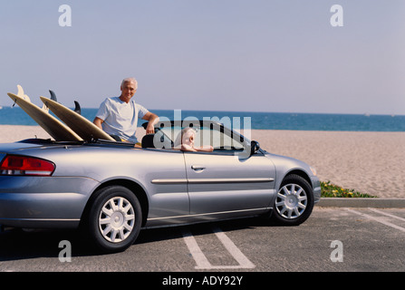 Paar in Covertible Auto mit Surfbrettern Stockfoto