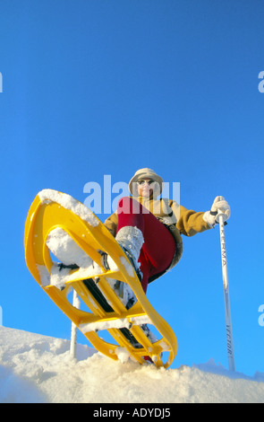 Frau Schneeschuhwandern, niedrigen Winkel Ansicht, gegen blauen Himmel Stockfoto