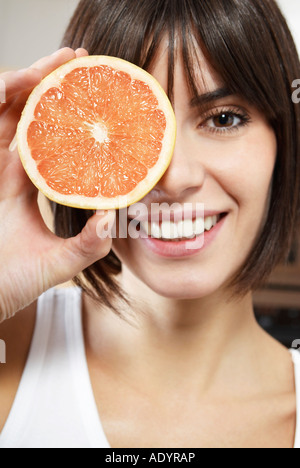 Frau, hält die Hälfte der Grapefruit vor Gesicht, Porträt, schließen sich Stockfoto