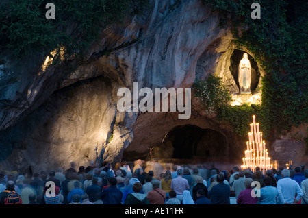 Pilger beten an der Grotte von Massabielle in Lourdes am Abend, Frankreich Stockfoto