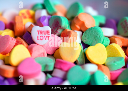 Kleine herzförmige Bonbons in einem Haufen mit wahrer Liebe, geschrieben auf einem Stockfoto