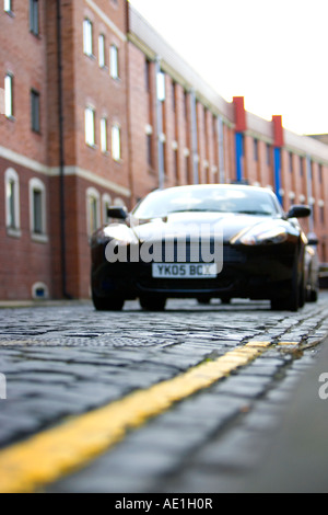 Grand Tourer schwarz Aston Martin DB9 in städtische Straße mit roten Ziegelsteinen geparkt und gepflasterten Gassen in wohlhabenden Leeds Stockfoto
