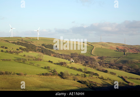 Ländliche Hügel mit einer Reihe von Windturbinen und Strom Übertragungsleitungen gegen einen blauen Himmel mit etwas Wolke Stockfoto