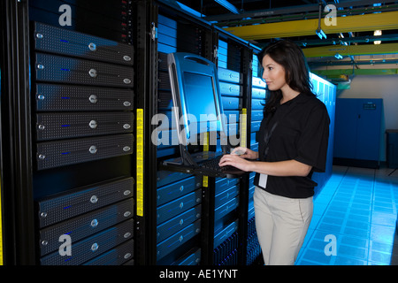 Eine junge Frau steht auf einem Computer in ein Lager mit Servern gefüllt. Stockfoto