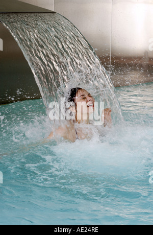 Junge Frau, die unter Wasserspray im Whirlpool Stockfoto