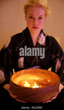 Junge Frau mit Holzschale mit brennenden Kerzen Stockfoto