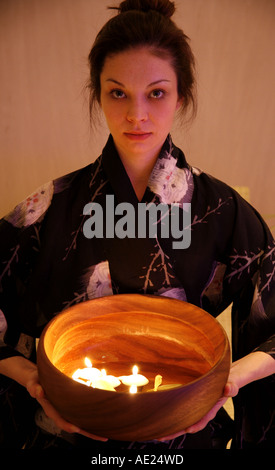 Junge Frau mit Holzschale mit brennenden Kerzen Stockfoto