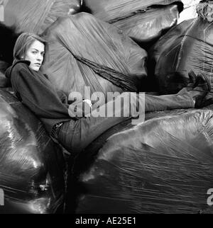 Porträt eines Mädchens sitzen auf schwarzen Silage Taschen im ländlichen Wales, UK KATHY DEWITT Stockfoto