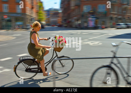 Eine Frau mit dem Fahrrad mit Körbchen Geranien in Mitteleuropa Kopenhagen Dänemark Stockfoto