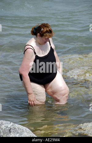 Beleibte Frau waten im Wasser Badeanzug Stockfoto