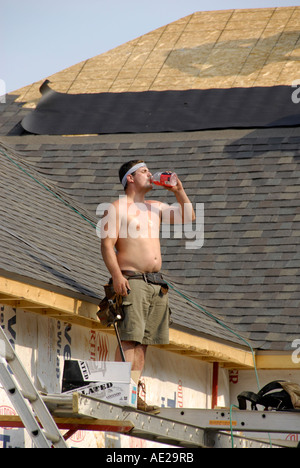 Hausbau-Besatzung fügt Dachschindeln auf dem Dach eines neuen Hauses Stockfoto
