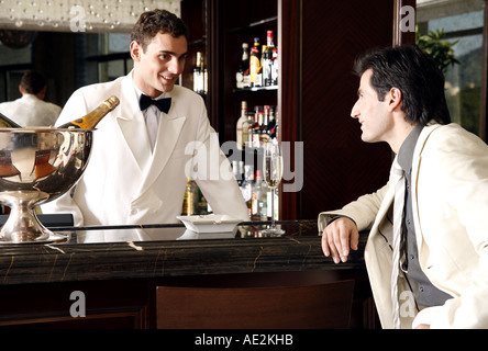 Mann sitzt in einer Bar im Gespräch mit der Barkeeper Stockfoto