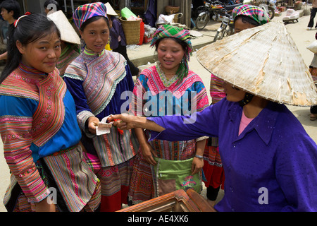 Flower Hmong junge Frau kaufen Eis Lutscher von konischen Hut Anbieter Bac Ha Bergvolk Markt Nord-Vietnam Stockfoto