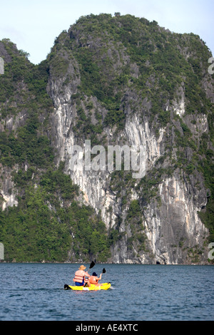 Kanuten paddeln unter emporragenden felsigen Inseln der Halong Bucht Vietnam Stockfoto