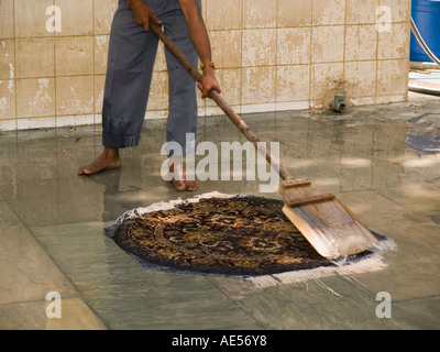 Demonstration der Herstellung Wollteppich mit asiatischer Mann Waschen fertig Wolle Teppich mit Wasser am Boden Stockfoto