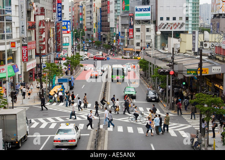 Belebte Straße in der Nähe von Bahnhof Shinjuku in Tokio mit Fußgängern, die Straße am Zebrastreifen überqueren Stockfoto